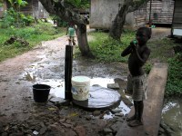 A child collecting water from the pipe